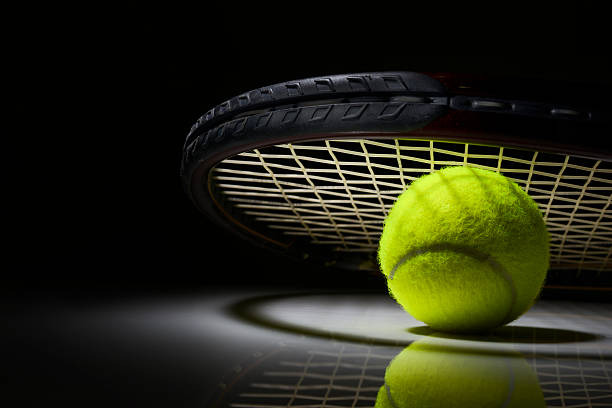 Tennis racket and ball on dark background